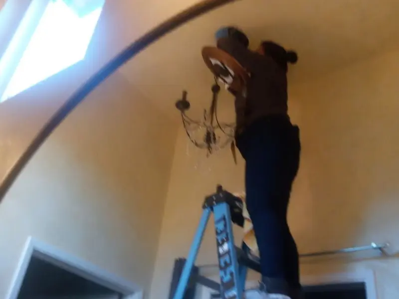 Electrician installing a chandelier in a Posen residence